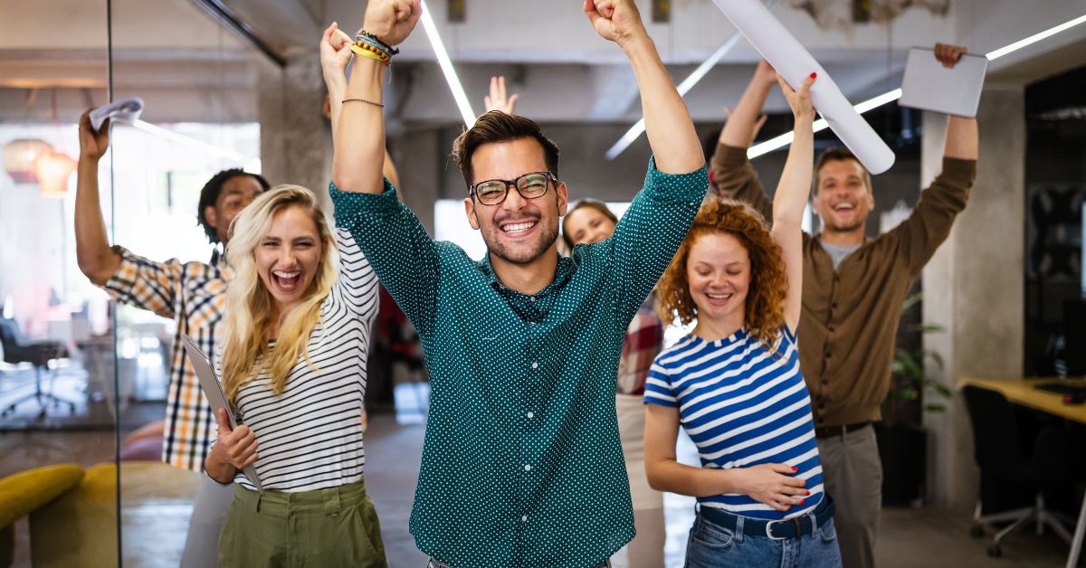 Happy, engaged employees celebrating in a modern office after successful HR consulting initiatives.